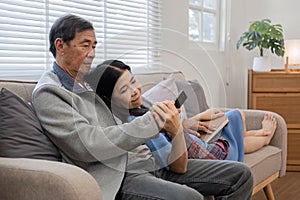 A senior couple in their 60s spends their free time relaxing and having fun together on the sofa in the living room.