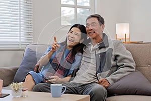 A senior couple in their 60s spends their free time relaxing and having fun together on the sofa in the living room.