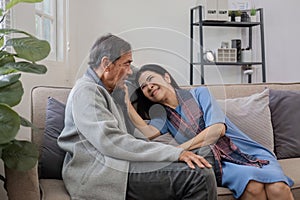 A senior couple in their 60s spends their free time relaxing and having fun together on the sofa in the living room.