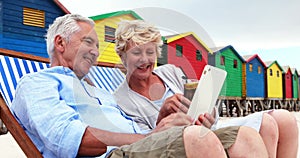 Senior couple using digital tablet at the beach