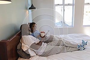 Senior couple using digital tablet while enjoying a cup of coffee in bedroom