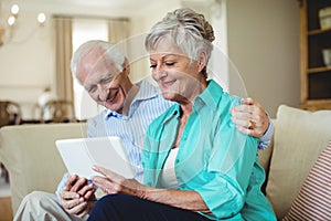 Senior couple using digital tablet in living room