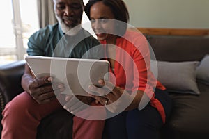 Senior couple using digital tablet in living room at home