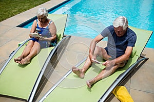 Senior couple using digital tablet on lounge chair photo