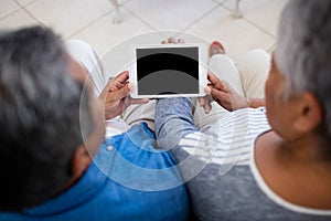 Senior couple using digital tablet while sitting in the living room