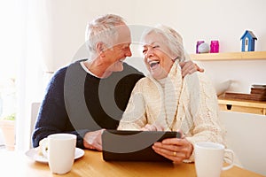 Senior Couple Using Digital Tablet At Table