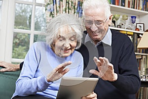 Senior Couple Using Digital Tablet For Video Call With Family