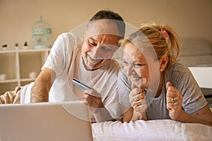 Senior couple using laptop in bed.