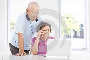 Senior couple using a laptop and a cell phone