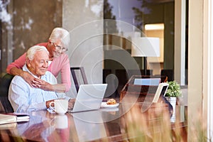 Senior Couple Using Laptop On Desk At Home