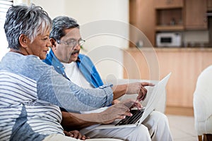 Senior couple using laptop in living room