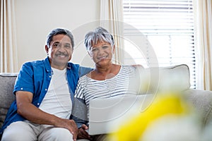 Senior couple using laptop in living room at home