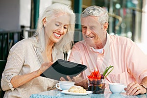 Senior Couple Using Tablet Computer Cafe