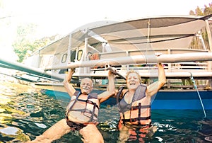 Senior couple vacationer having genuine playful fun at beach in Philippines - Snorkel boat trip in exotic scenario - Active photo