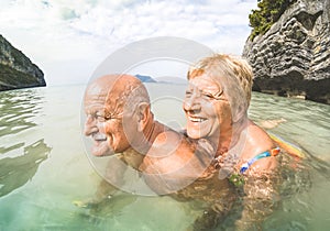Senior couple vacationer having genuine playful fun on tropical beach photo