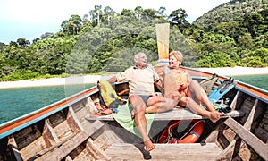 Senior couple vacationer relaxing at island hopping tour after beach exploration during snorkel boat trip in Thailand - Active