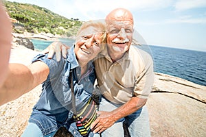 Senior couple vacationer taking selfie while having genuine fun at Giglio Island - Excursion tour in seaside scenario