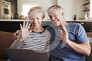 Senior couple video calling on a laptop waving at screen