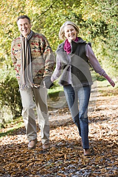 Senior couple walking through autumn woods photo