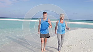 Senior Couple Walking On Beautiful Beach
