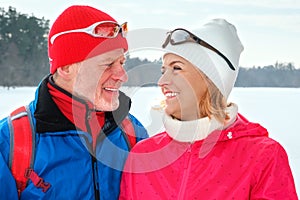 Senior couple walking with nordic walking poles in snowy winter park