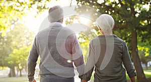 Senior couple, walking and outdoor at a park with a love, care and support from back. A elderly man and woman holding