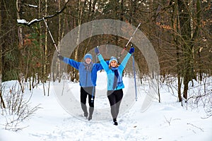 Senior couple walking with outstretched arms in snowy winter park