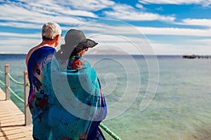 Senior couple walking on pier by Red sea covered with pareo. People enjoying vacation. Valentine`s day