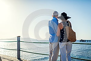 Senior couple walking on pier by Red sea. People enjoying summer vacation