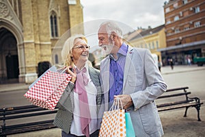 Senior couple walking with their shopping purchases on a sunny day