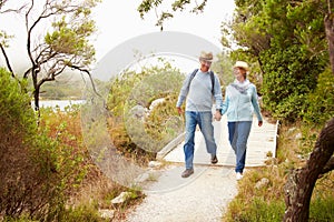 Senior couple walking together on a path by a lake