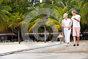 Senior Couple Walking On Wooden Jetty