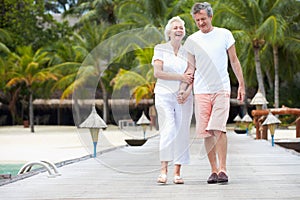 Senior Couple Walking On Wooden Jetty