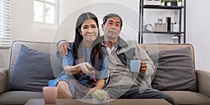 Senior couple watching tv and sofa in relax for movie or series in living room at home. Elderly man and woman with