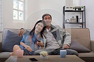 Senior couple watching tv and sofa in relax for movie or series in living room at home. Elderly man and woman with