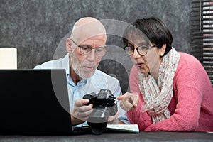 Senior couple watching vacation pictures on camera