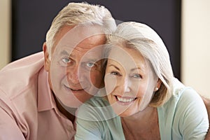 Senior Couple Watching Widescreen TV At Home