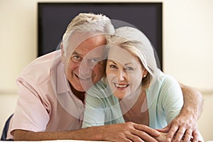 Senior Couple Watching Widescreen TV At Home