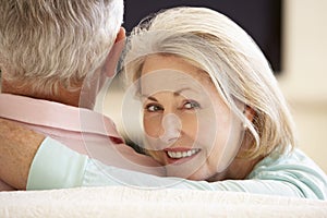 Senior Couple Watching Widescreen TV At Home