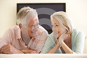 Senior Couple Watching Widescreen TV At Home