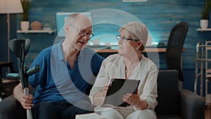 Senior couple waving at tablet webcam on online video call
