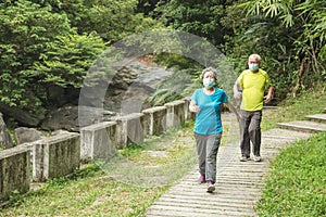 Senior couple wearing face mask and walking trough nature park