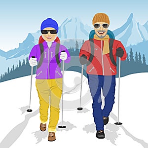 Senior couple wearing hiking gear walking in mountains in winter