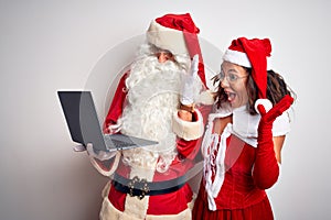 Senior couple wearing Santa Claus costume using laptop over isolated white background very happy and excited, winner expression