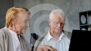 Senior couple websurfing on internet with laptop. Happy elderly man and woman using computer