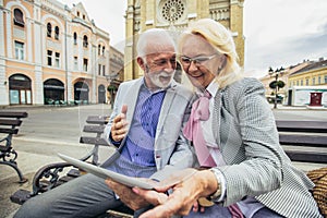 Senior couple websurfing on internet with tablet outdoor
