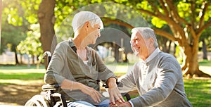 Senior couple, wheelchair and happy outdoor at a park while talking with love, care and respect. A elderly man and woman