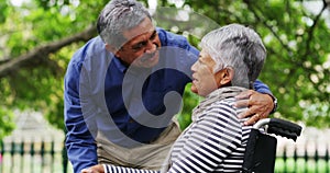 Senior couple, wheelchair and outdoor at a park with love, support and care in retirement. A elderly man and woman with