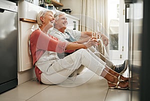 Senior couple, wine and laughing on kitchen floor thinking happy memories and talking about love during a celebration of