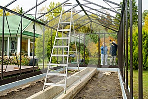 Senior couple working on a project in their garden. Man and woman constructing a greenhouse in their backyard